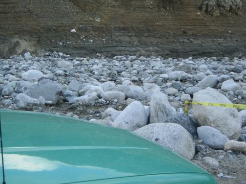 1987 Suzuki Samurai - A green vehicle is parked in a rocky area, possibly a dry riverbed, with caution tape visible in the background.
