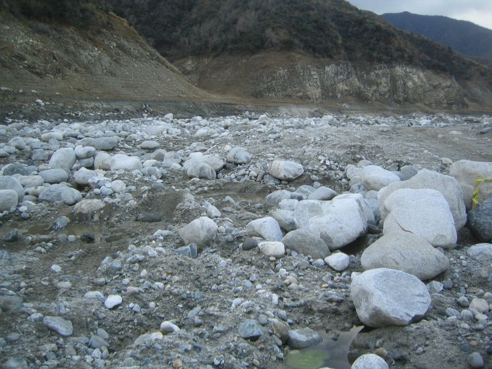 Rocky terrain with scattered boulders and dry earth under a cloudy sky
