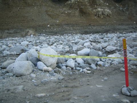1987 Suzuki Samurai - A red post with trail signs stands near yellow caution tape laid across a rocky, dry riverbed.