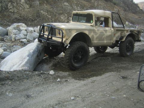 1987 Suzuki Samurai - This Jeep M715 navigates a rocky, off-road terrain with its front tire perched on a large boulder.