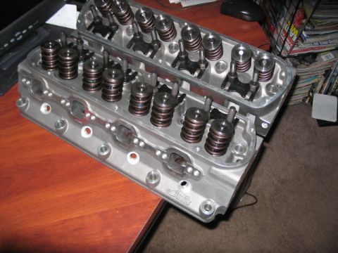 1991 Ford Bronco - Two engine cylinder heads are shown on a desk, with valve springs and retainers clearly visible.