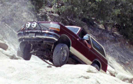 1993 Ford Bronco - A 1993 Ford Bronco navigates a steep, rocky terrain, its off-road capabilities.