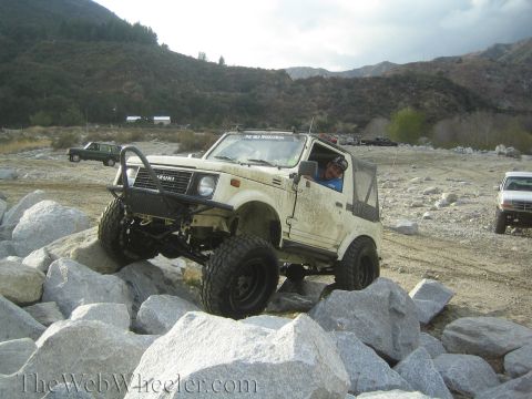 1987 Suzuki Samurai - Suzuki Samurai tackling a challenging rocky terrain with another vehicle in the background.