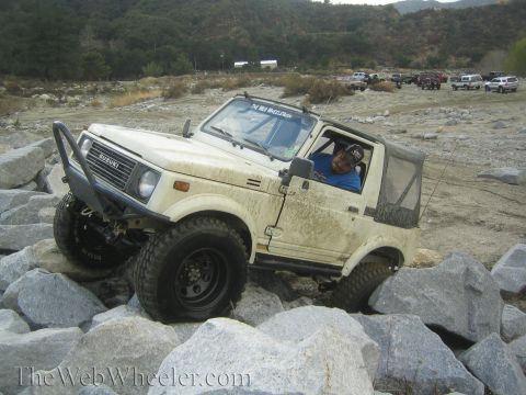 1987 Suzuki Samurai - Suzuki Samurai tackling a challenging rocky terrain, with other vehicles visible in the background.