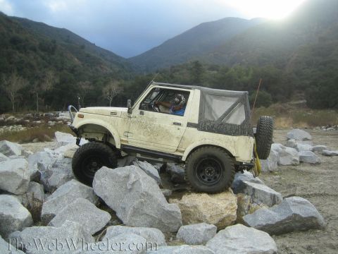 1987 Suzuki Samurai - A Suzuki Samurai navigates a rocky terrain with a driver wearing a helmet.