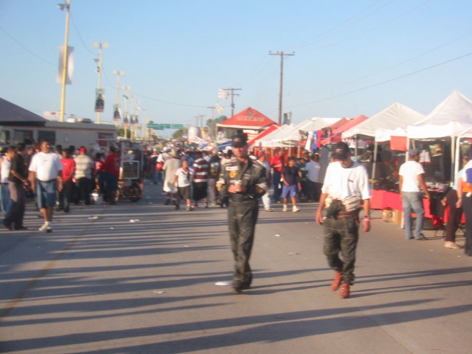 Crowded street scene with tents and people walking, clear sky