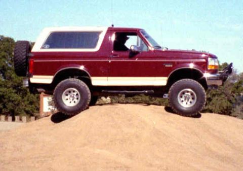 1993 Ford Bronco - This 1993 Ford Bronco is shown in a side profile, its distinctive red body with a white removable top and a spare tire mounted on the rear.
