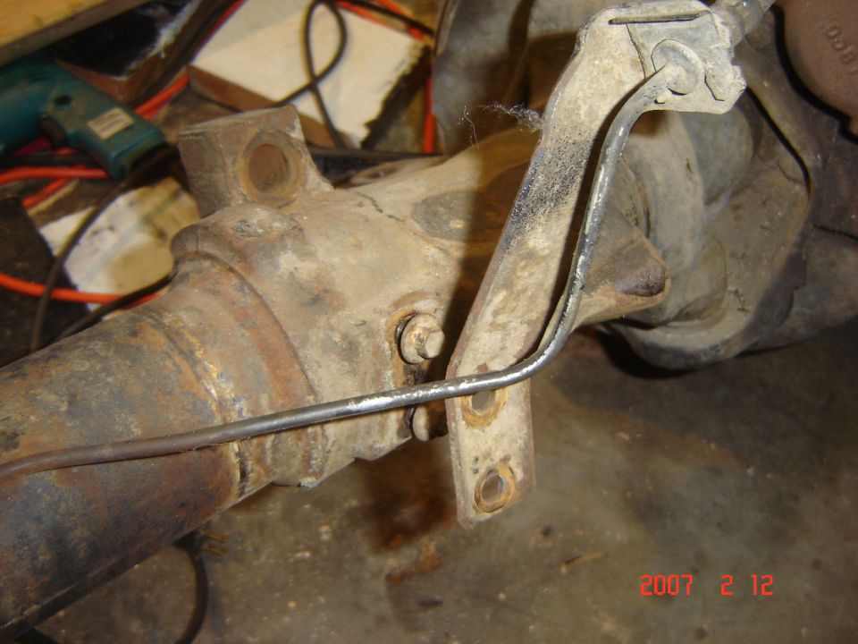 Close-up of a rusty rear axle assembly showing a brake line bracket attached with bolts