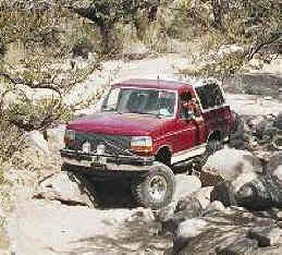 1993 Ford Bronco - This red 1993 Ford Bronco is shown off-roading on a rocky trail.