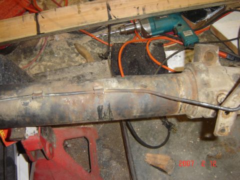 1993 Ford Bronco - A close-up shows a rusty vehicle axle assembly supported by a red jack stand, with tools and electrical cords in the background.