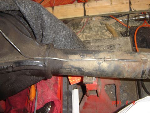 1993 Ford Bronco - Close-up view of a vehicle's rear axle assembly supported by red jack stands, with various tools and wiring visible in the background.
