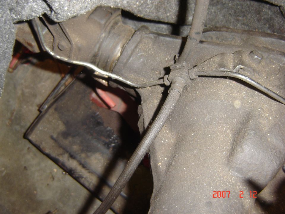 Close-up of vehicle transmission housing with brake lines and cables attached