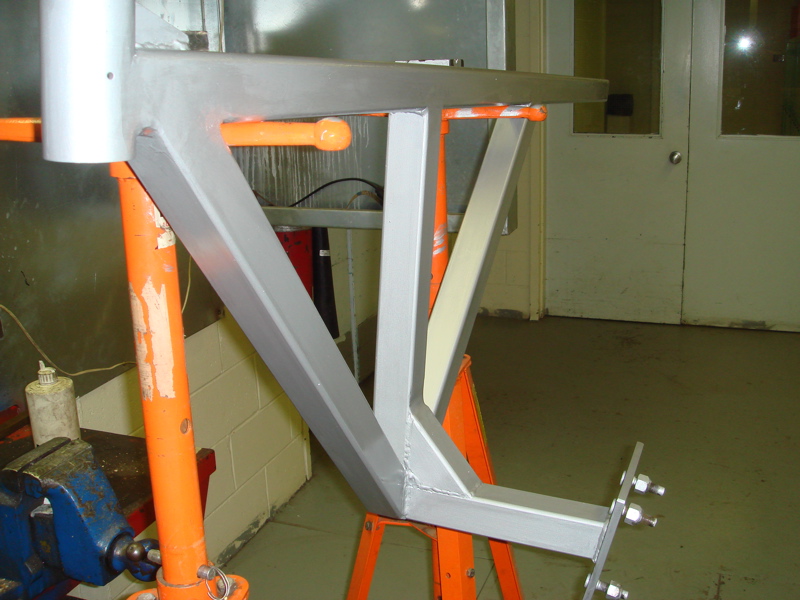 Metal frame assembly with bolts, supported by orange stands and a vise