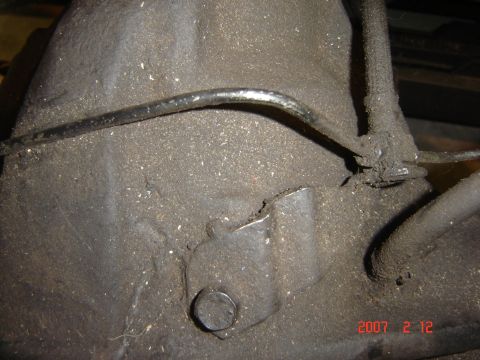1993 Ford Bronco - A close-up view of a heavily soiled transmission housing, showing a metal line and some mounting points.