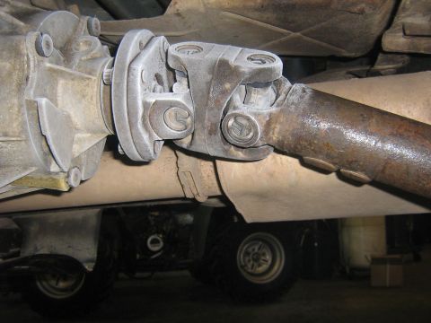 1995 Ford Bronco - Underside view of a vehicle's driveshaft and transfer case assembly.