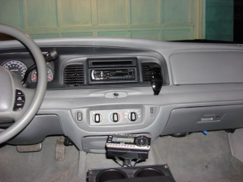 2003 Ford Crown Victoria - The dashboard of a car displays two radios, one integrated into the dash and another mounted below, alongside the steering wheel.