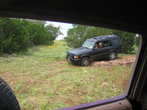 1996 Ford Bronco - A black Land Rover Discovery SUV is seen off-road, with a person visible inside the driver's seat.