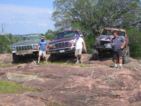 1996 Ford Bronco - Three trucks are parked on a rocky landscape with people standing around them.