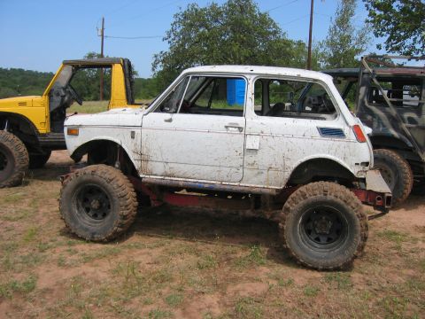 1996 Ford Bronco - A white off-road vehicle with large tires is parked next to a yellow off-road vehicle.