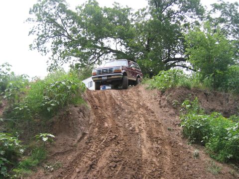 1996 Ford Bronco - Maroon 1996 Ford Bronco navigates a challenging muddy hill.