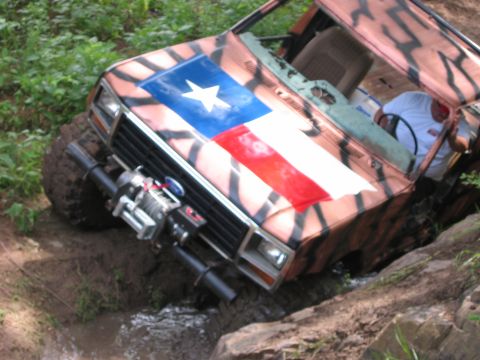 1996 Ford Bronco - This heavily modified off-road vehicle, painted with a Texas flag design, appears to be stuck in a muddy, rocky terrain.