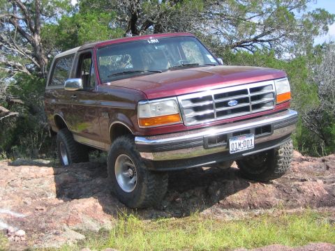 1996 Ford Bronco - A maroon Ford Bronco navigates a rocky terrain.