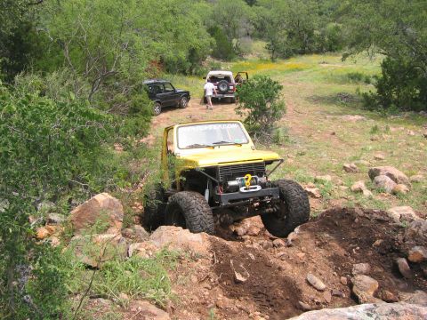 1996 Ford Bronco - Multiple off-road vehicles traverse a rocky, wooded trail.
