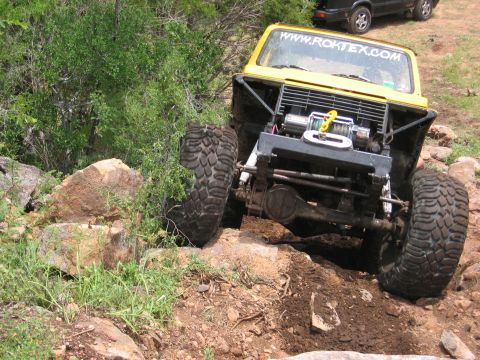 1996 Ford Bronco - This yellow off-road vehicle is equipped with a winch and is shown navigating a challenging rocky course.
