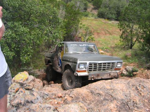 1996 Ford Bronco - This modified Ford pickup truck is shown off-roading over large rocks and dirt.