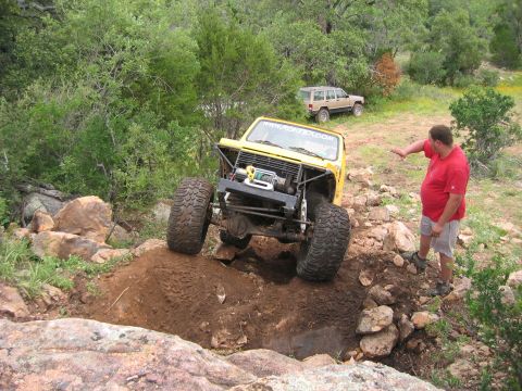 1996 Ford Bronco - A yellow off-road vehicle navigates a rocky terrain, with a man observing the action.