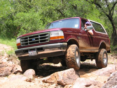 1996 Ford Bronco - This Ford Bronco is navigating a rocky off-road course, with mud splattered on its body.