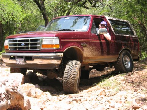 1996 Ford Bronco - This 1996 Ford Bronco is shown off-roading on a dirt and rock path, with mud splattered on its side.