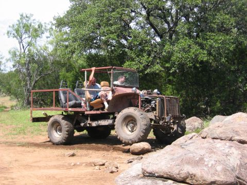 1996 Ford Bronco - Two people ride in a heavily modified off-road vehicle on a rocky trail.
