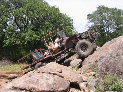 1996 Ford Bronco - A heavily modified off-road vehicle navigates a rocky terrain with a driver at the wheel.