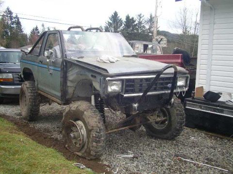 1984 Ford Bronco II - This heavily modified Ford Bronco II sits parked next to a building, showing off its off-road capabilities.