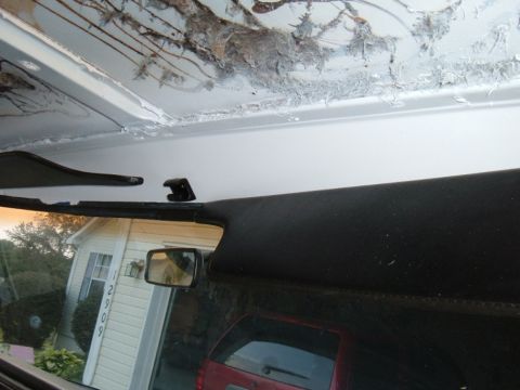 1978 Ford Bronco - The damaged headliner and interior components are visible, with a house and another vehicle seen through the windshield.
