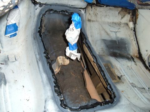 1978 Ford Bronco - Close-up view of the interior floor pan, showing a cut-out section and exposed drivetrain tunnel, with protective coverings.