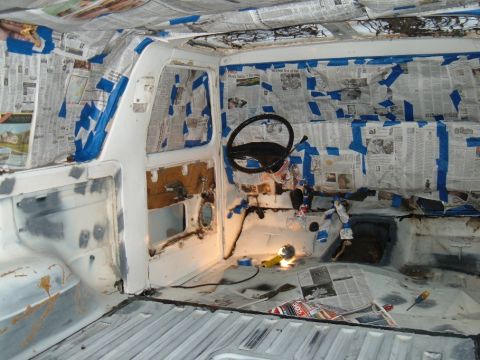 1978 Ford Bronco - Interior of a 1978 Ford Bronco being prepped for paint, with newspaper and tape covering surfaces.