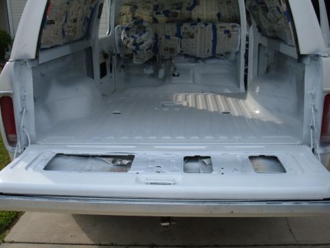 1978 Ford Bronco - The interior of a white SUV is prepared for work, with seats covered and the tailgate down.