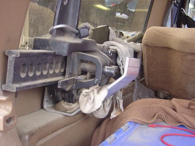 Hi-lift jack mounted on the interior panel of a vehicle, next to a tan seat and covered in dust