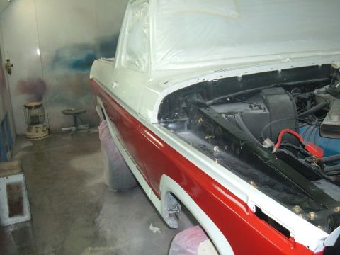 1978 Ford Bronco - A two-tone red and white pickup truck is being prepped for paint in a booth, with its hood open to reveal the engine bay.