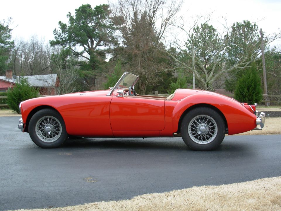Red 1959 MG A convertible sports car, side view, wire wheels, tan interior, parked on asphalt