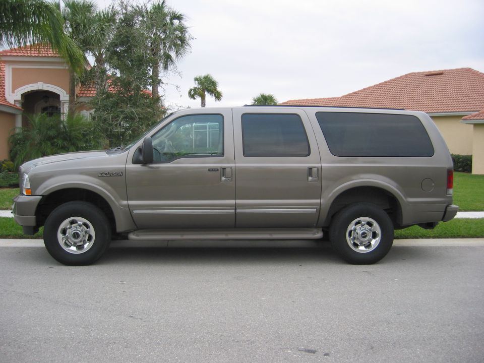Tan Ford Excursion SUV side profile on residential street