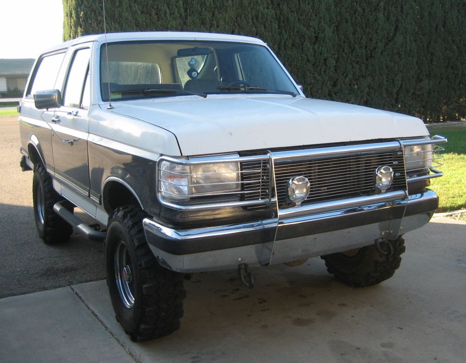 Lifted white and dark two-tone Ford Bronco with chrome brush guard, front 3/4 view