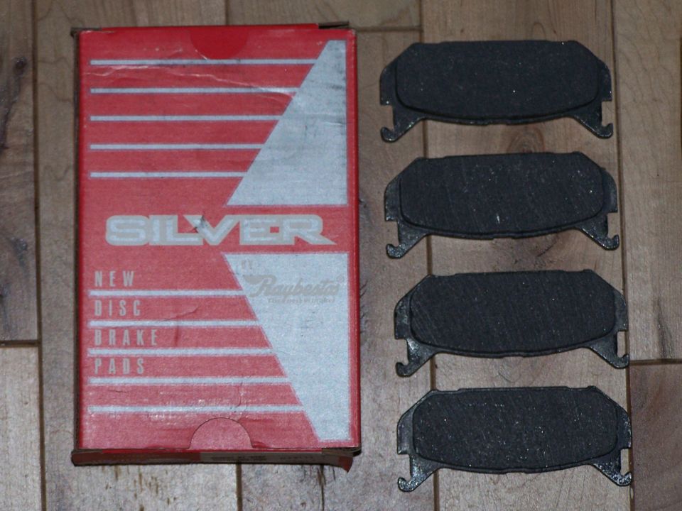 Silver brand new disc brake pads in red box, with four pads shown