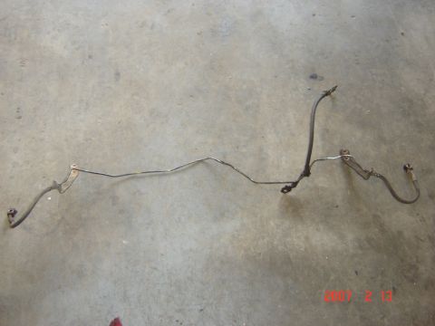 1993 Ford Bronco - A brake line assembly lies on a concrete surface, likely removed from a vehicle.