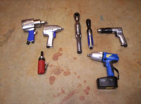 1995 Ford Bronco - Various pneumatic and electric power tools, including impact wrenches and ratchets, are laid out on a stained concrete surface.