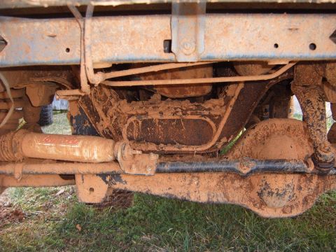 1988 Ford Bronco - The undercarriage of a heavily muddied truck, revealing suspension components and the rear differential.