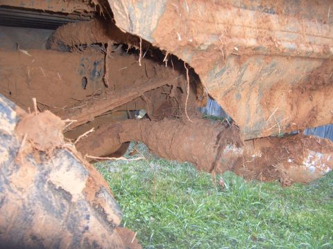 1988 Ford Bronco - The undercarriage of a vehicle is heavily covered in mud, obscuring most details.