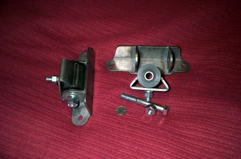 1996 Ford Bronco - Two engine mounts and assorted hardware are displayed on a red textured surface, with a coin for scale.